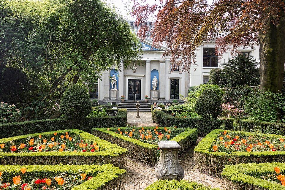 Formal garden with geometric flower beds and a stately white building in the background