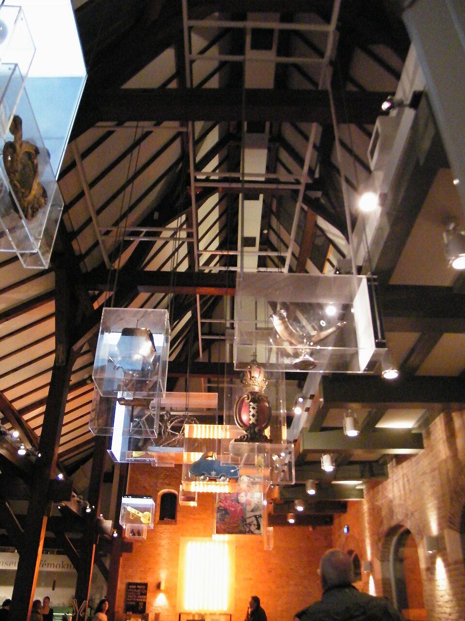 Industrial interior with exposed beams, brick walls, hanging lights, and reflective ceiling panels.