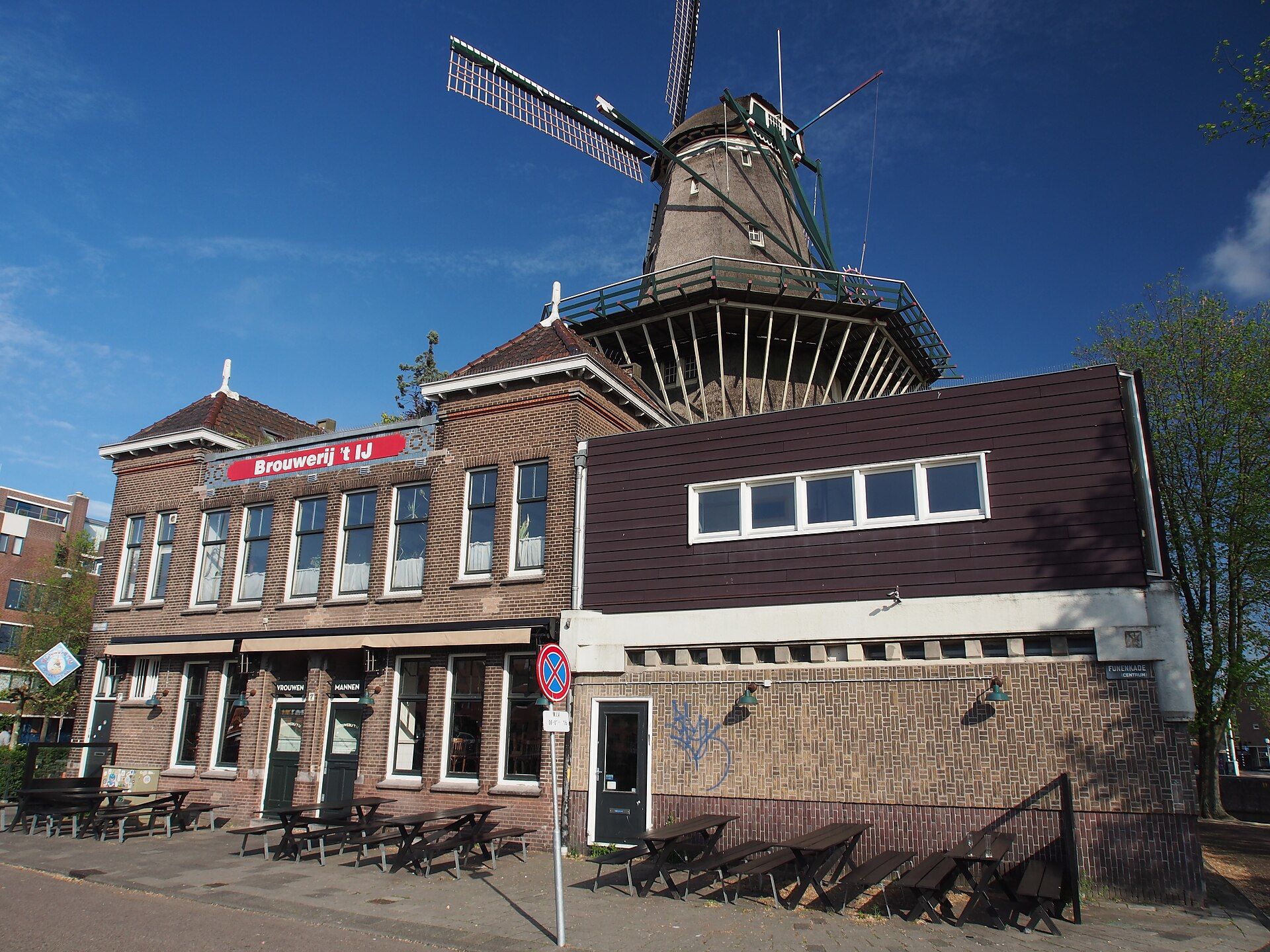 Historic brick building with a windmill tower under a clear blue sky