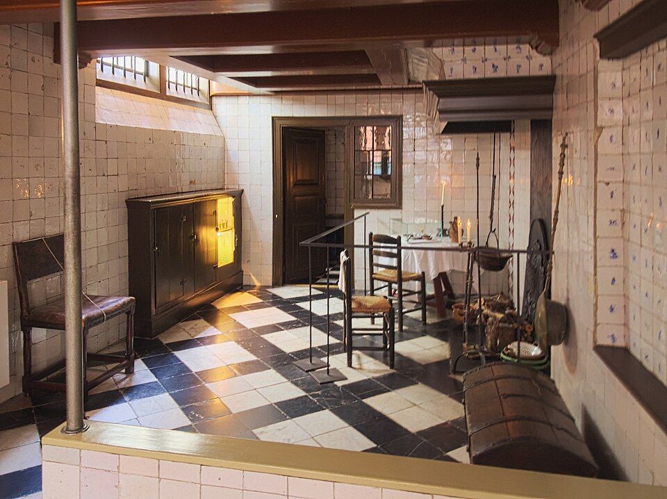 Rustic tiled room with a fireplace, black-and-white floor tiles, and wooden furniture in warm sunlight