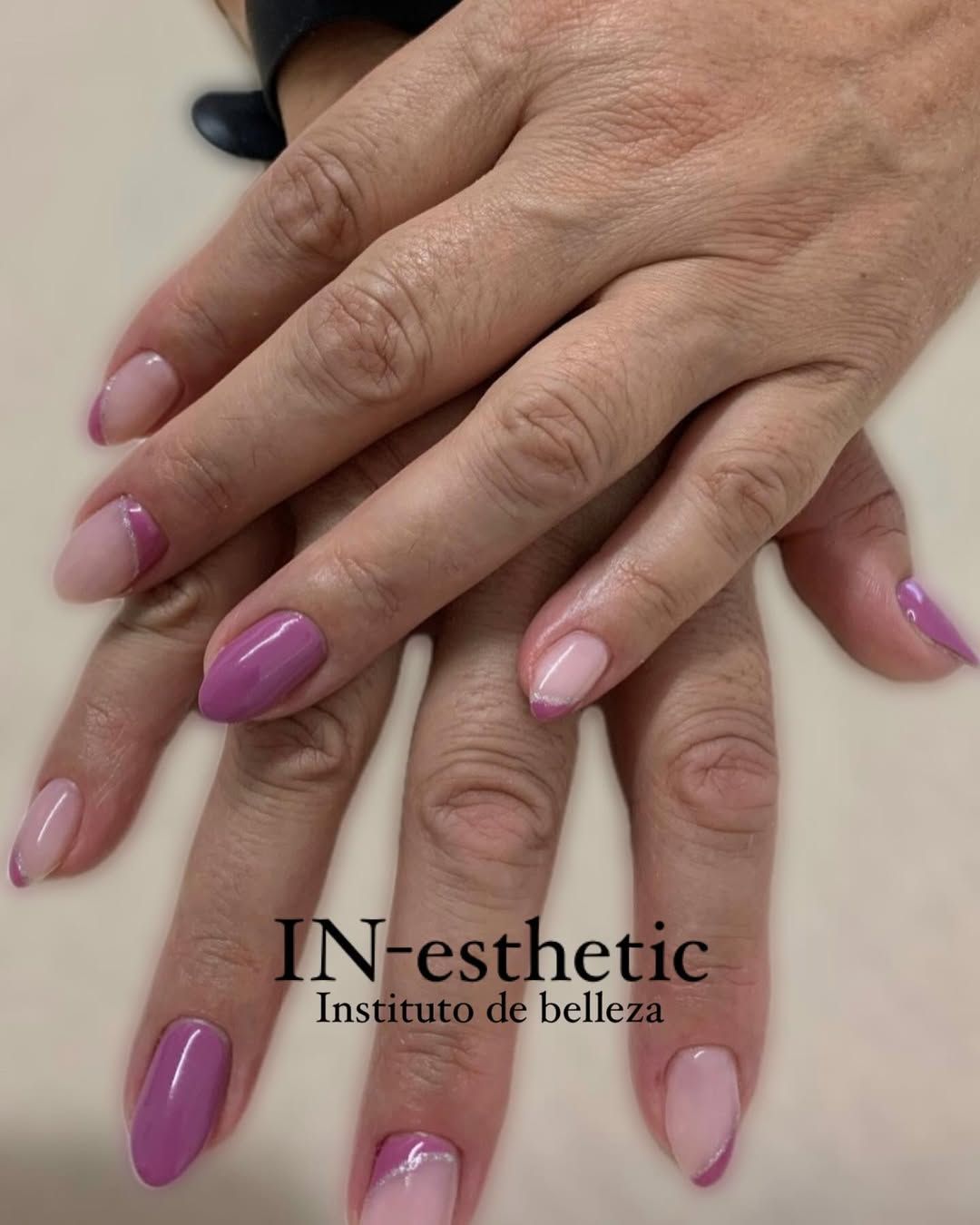 Un primer plano de las manos de una mujer con uñas moradas y rosas.