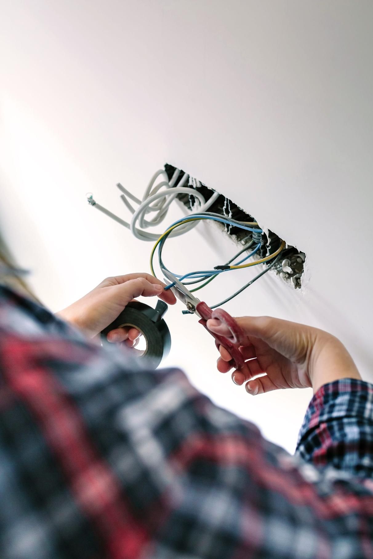 Persona que realiza conexiones eléctricas en una lámpara de techo con un destornillador.