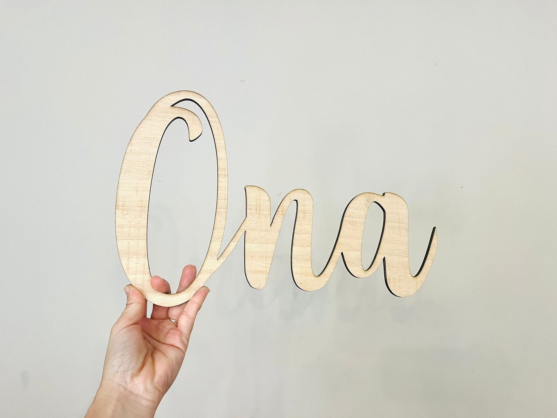 Una mano sostiene una figura de madera con el nombre 