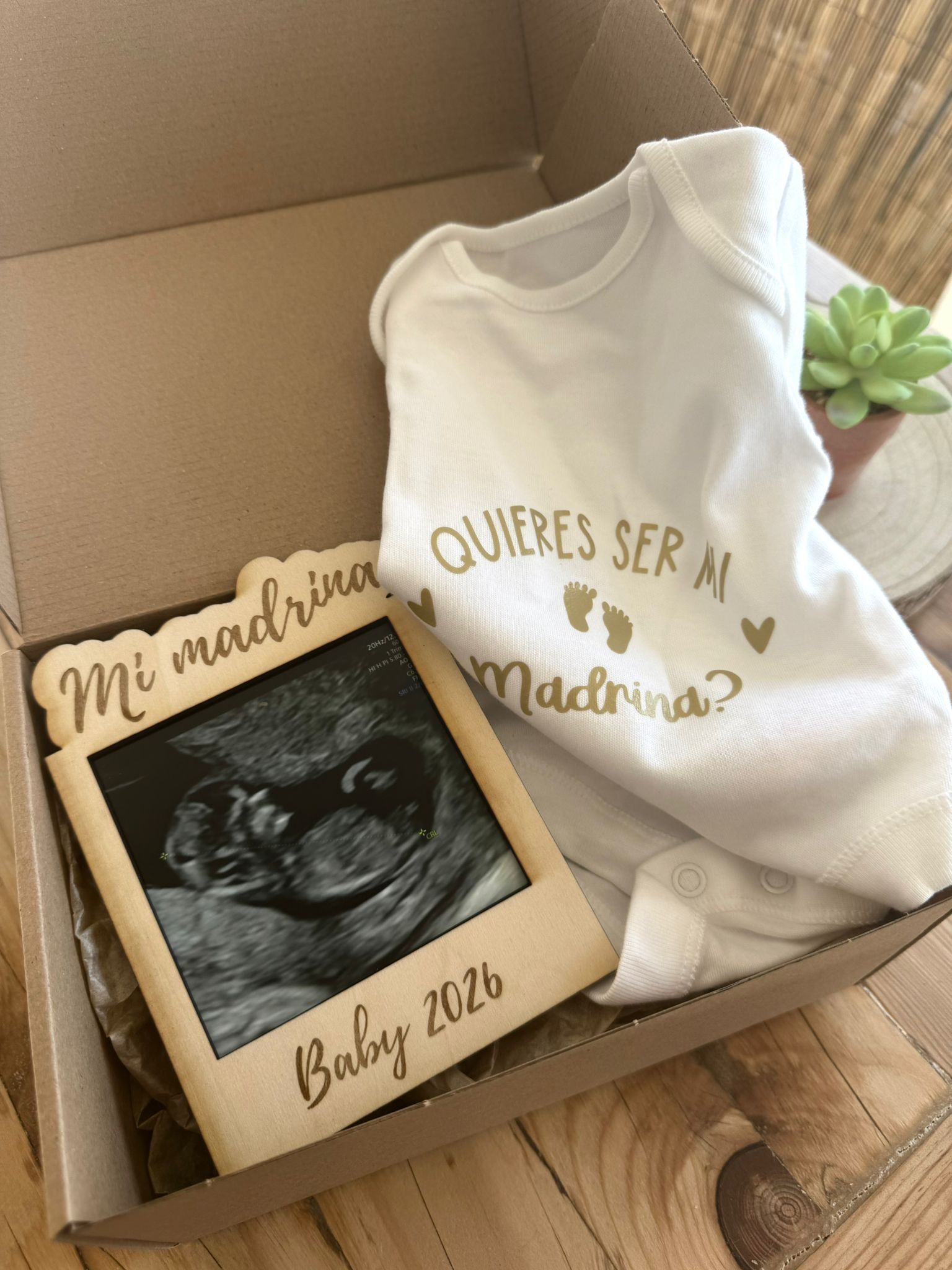 Una caja de regalo que contiene un body blanco para bebé estampado con 