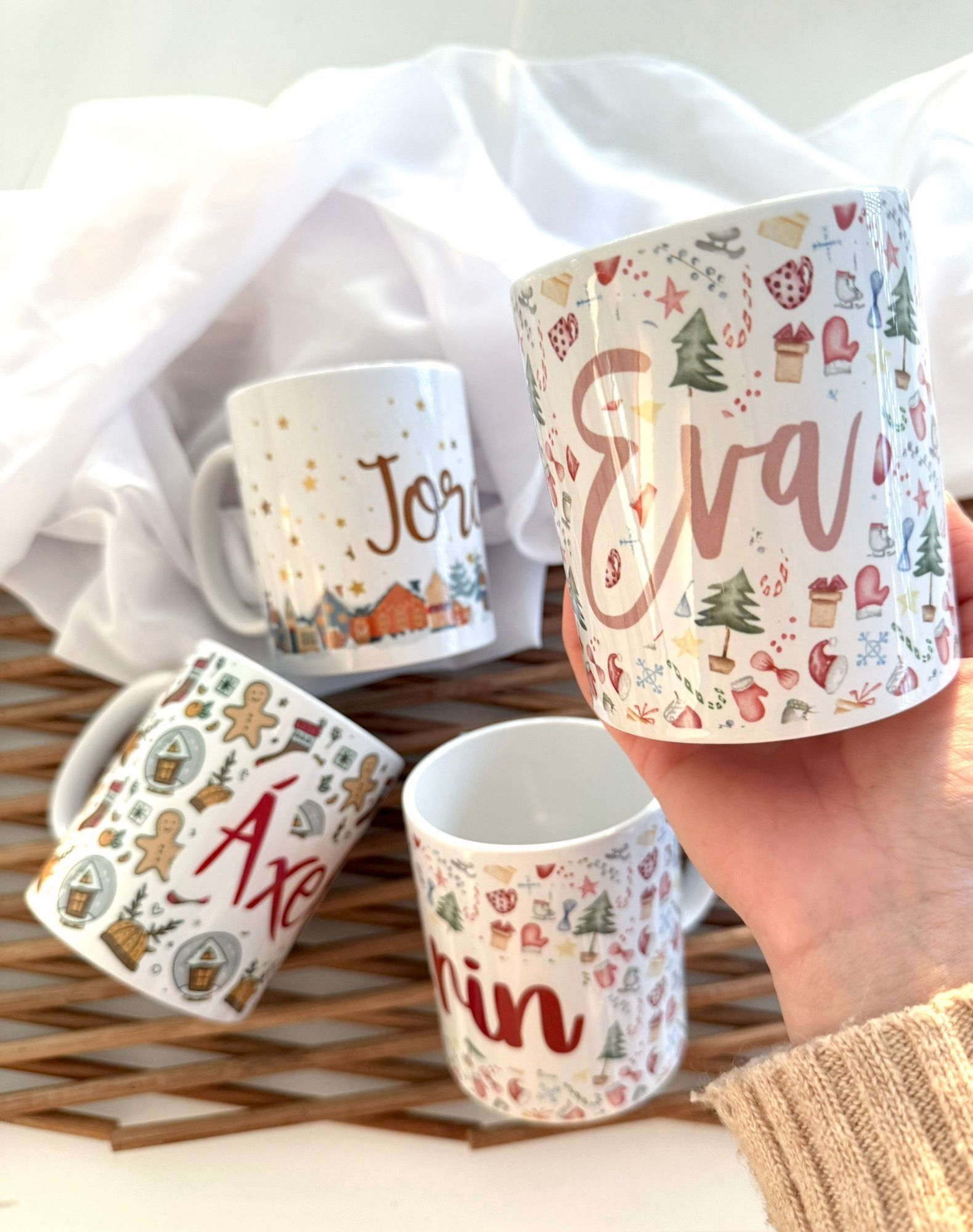 Una mano sostiene una taza personalizada con motivos navideños que lleva impreso el nombre 