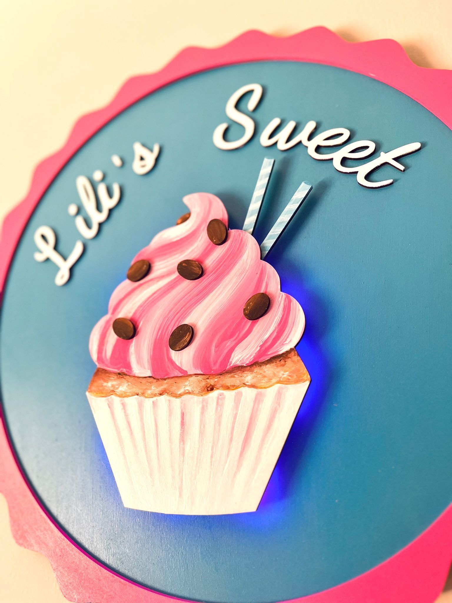 Un letrero redondo con un borde festoneado rosa y fondo azul dice 