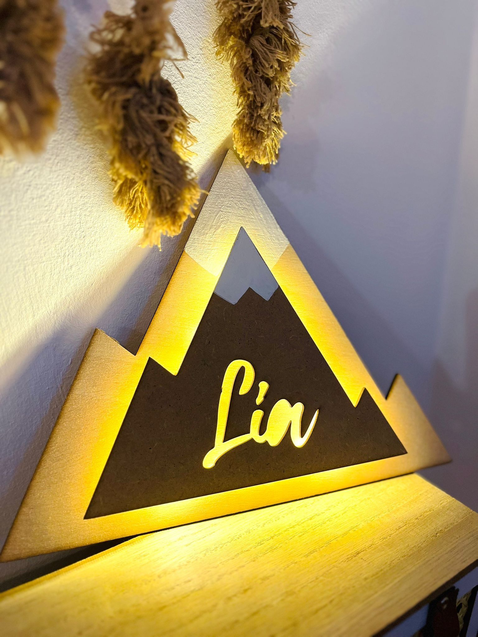 Un letrero con forma de montaña, retroiluminado en amarillo, que muestra el nombre 