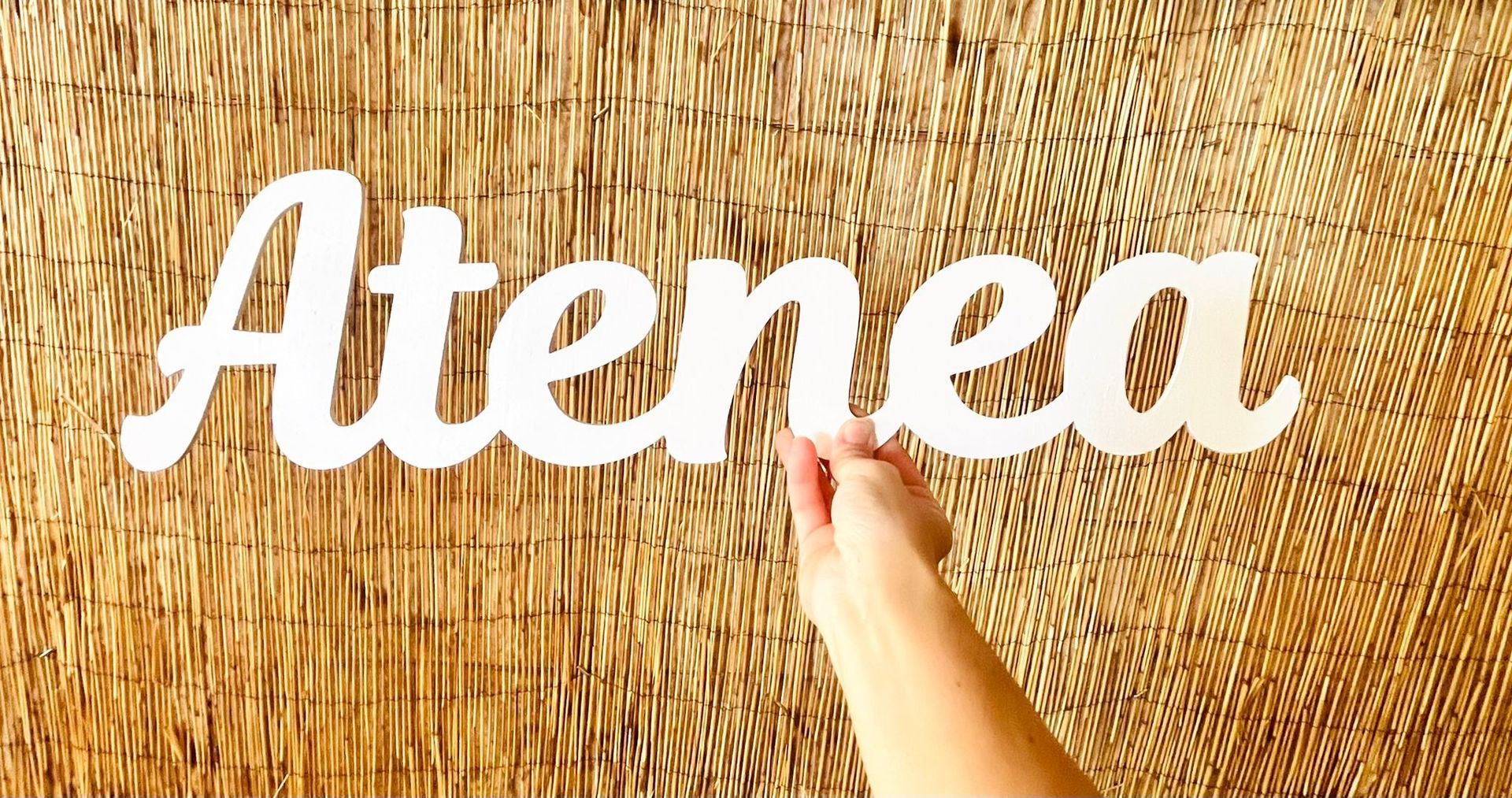 Una mano sostiene un letrero blanco en letra cursiva que dice 