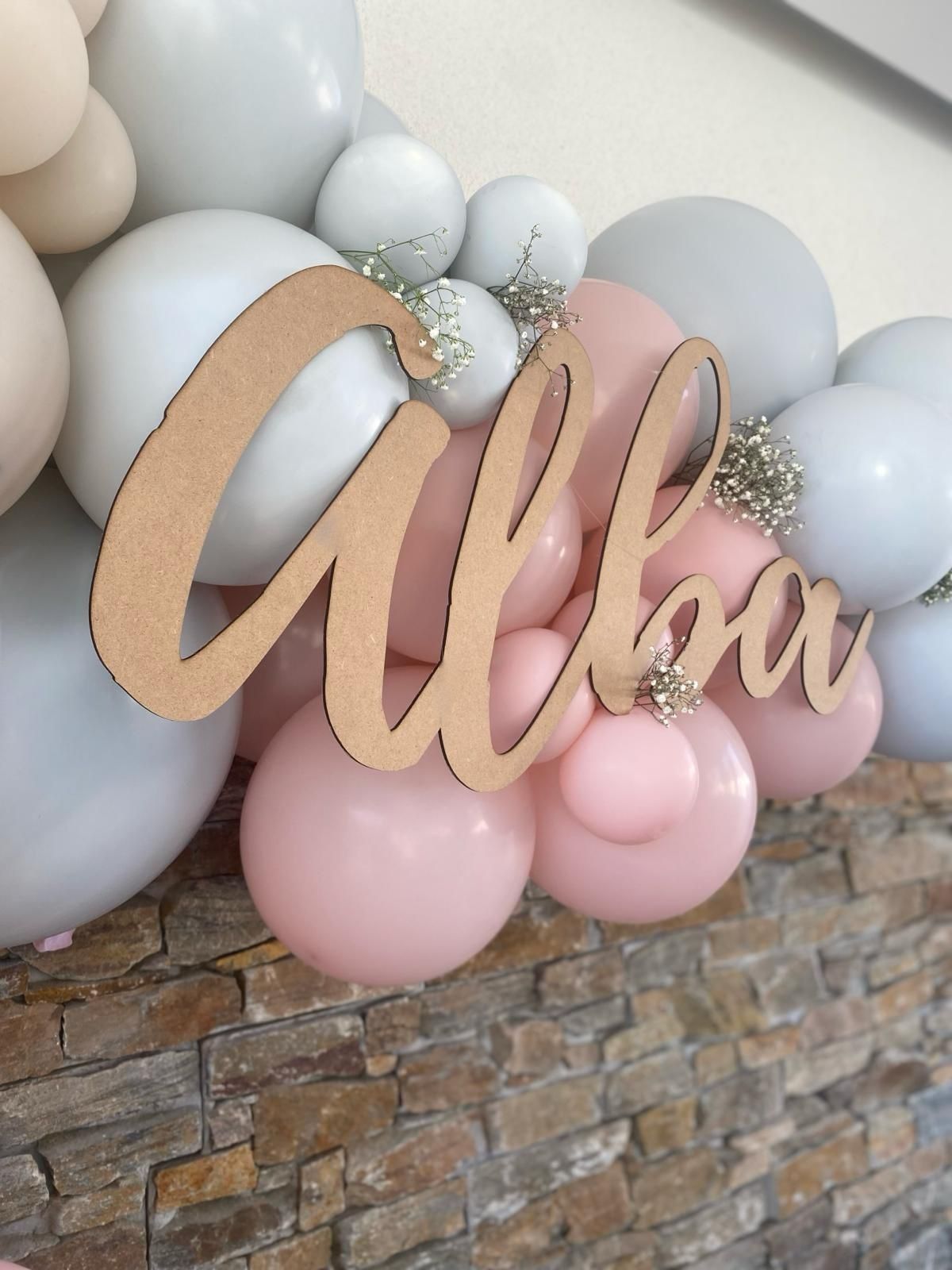 Un arco de globos en blanco, beige y rosa, con un letrero dorado brillante que dice 