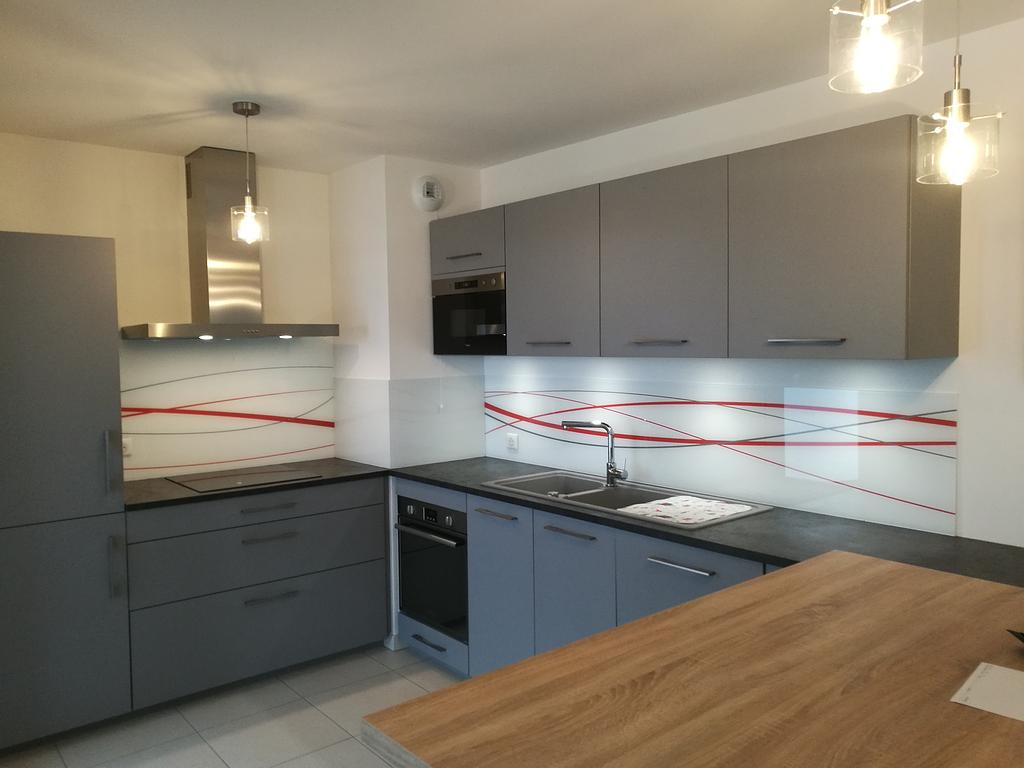 Cuisine grise moderne avec électroménagers en acier inoxydable, crédence à motifs et comptoir en bois.