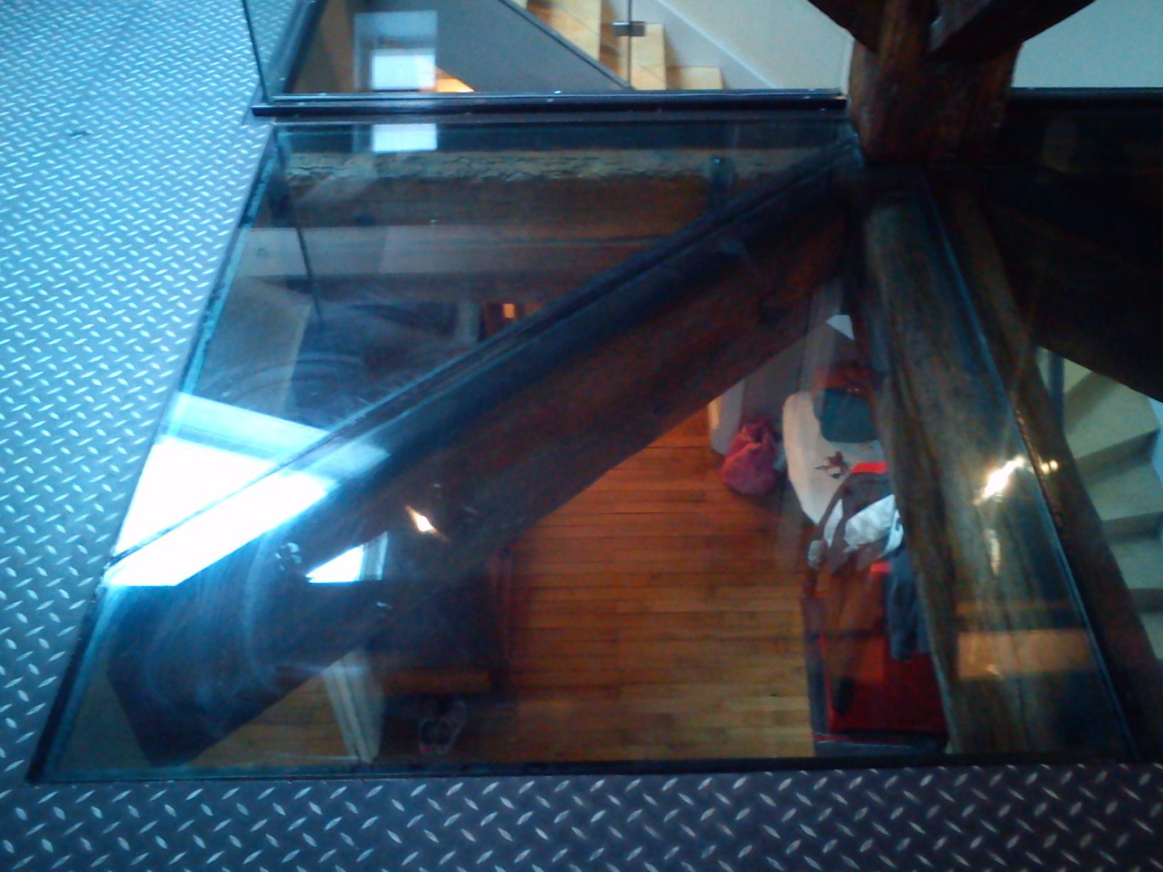 Dalle de sol en verre transparent donnant sur une pièce avec du parquet.