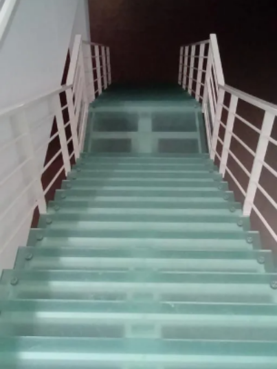 Escalier moderne en verre transparent avec rambardes métalliques blanches.