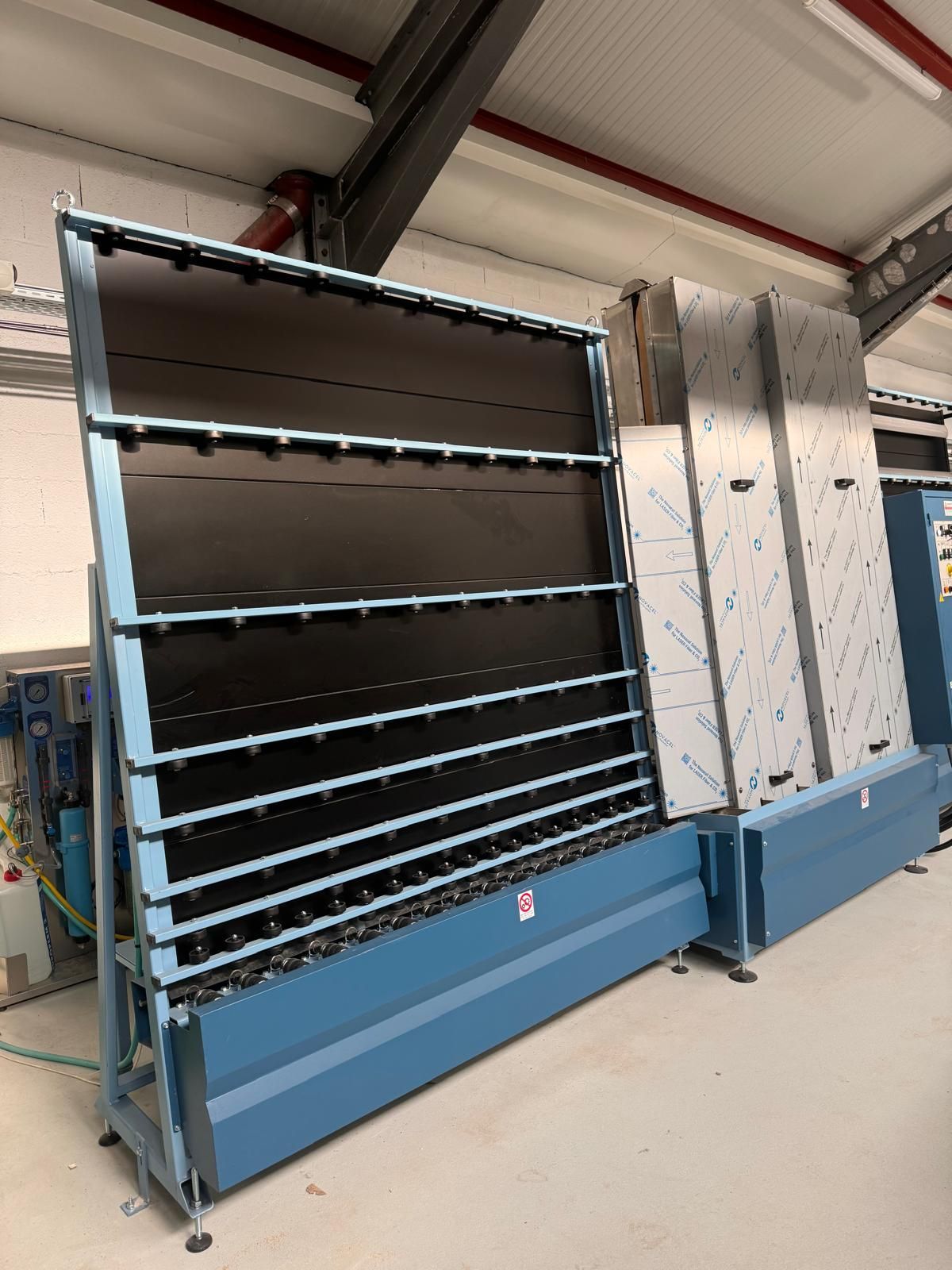 Grande machine industrielle bleue et en acier inoxydable avec de grandes plaques de verre.