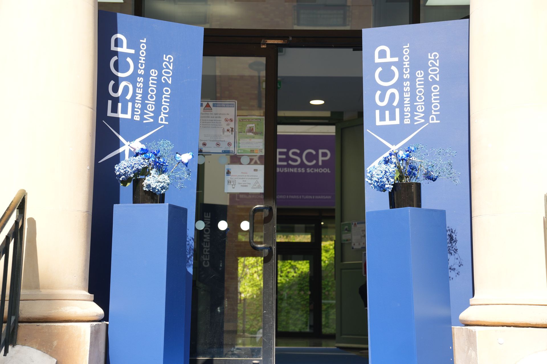 Entrée du bâtiment de l'ESCP avec des bannières bleues et des portes vitrées