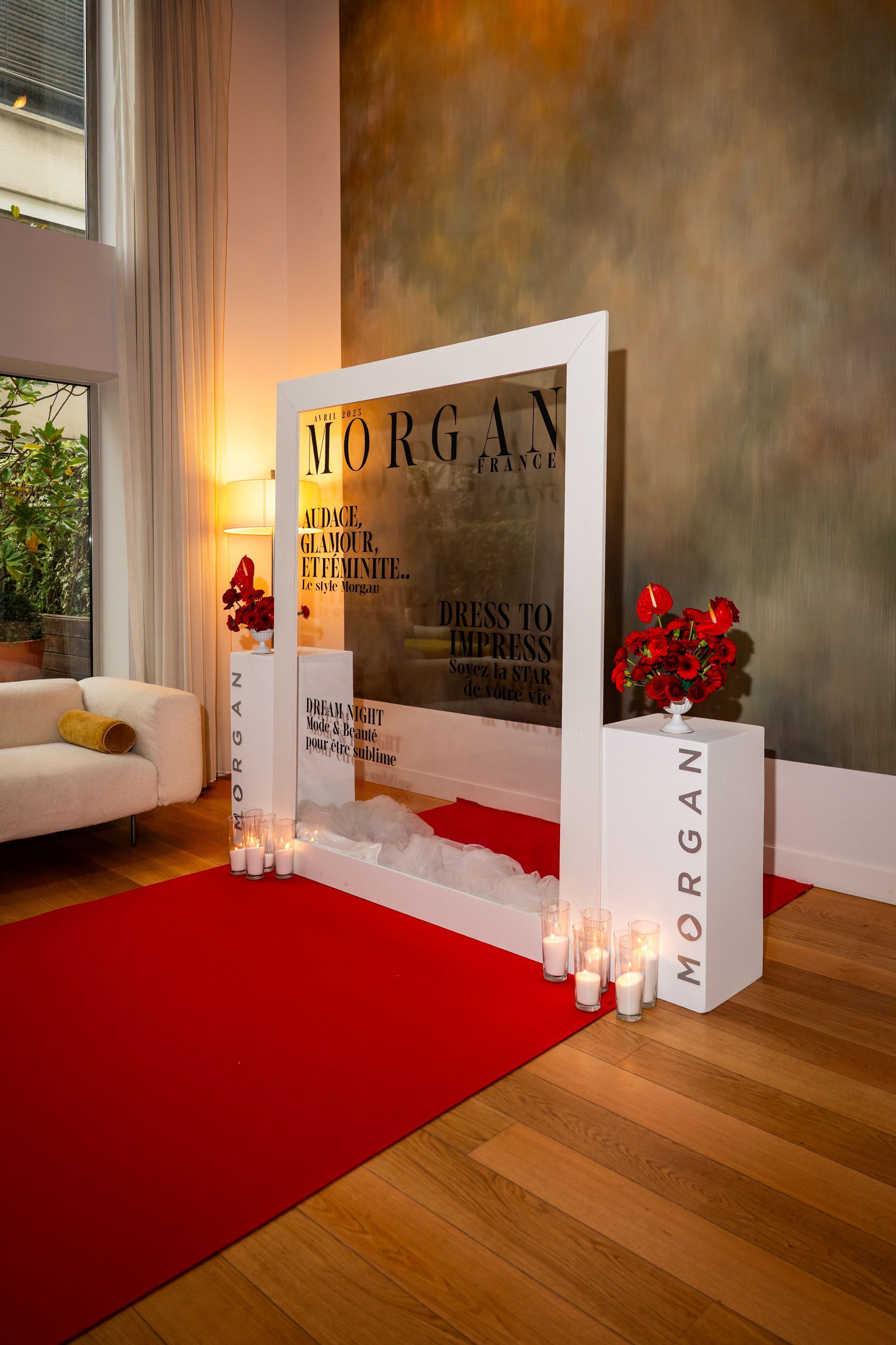 Décoration élégante dans un hall d'entrée : tapis rouge, cadre blanc, bougies et fleurs rouges à côté d'un grand vase.