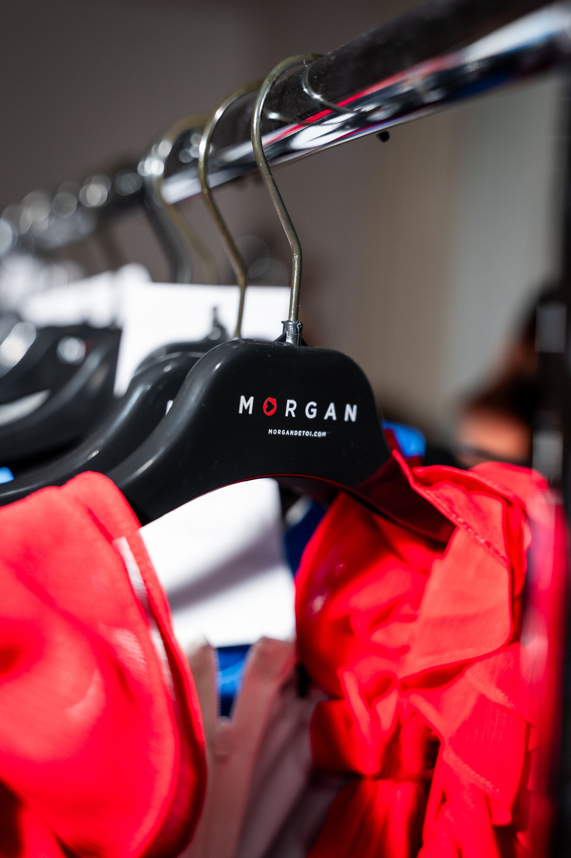 Vêtements rouges sur un cintre Morgan noir, suspendus à un portant