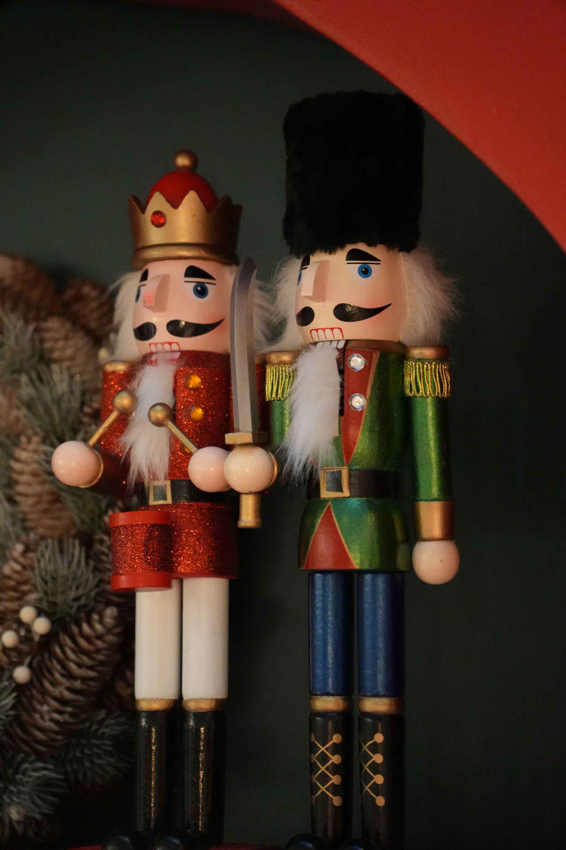 Deux figurines décoratives de casse-noisettes rouges, vertes et dorées sur fond sombre