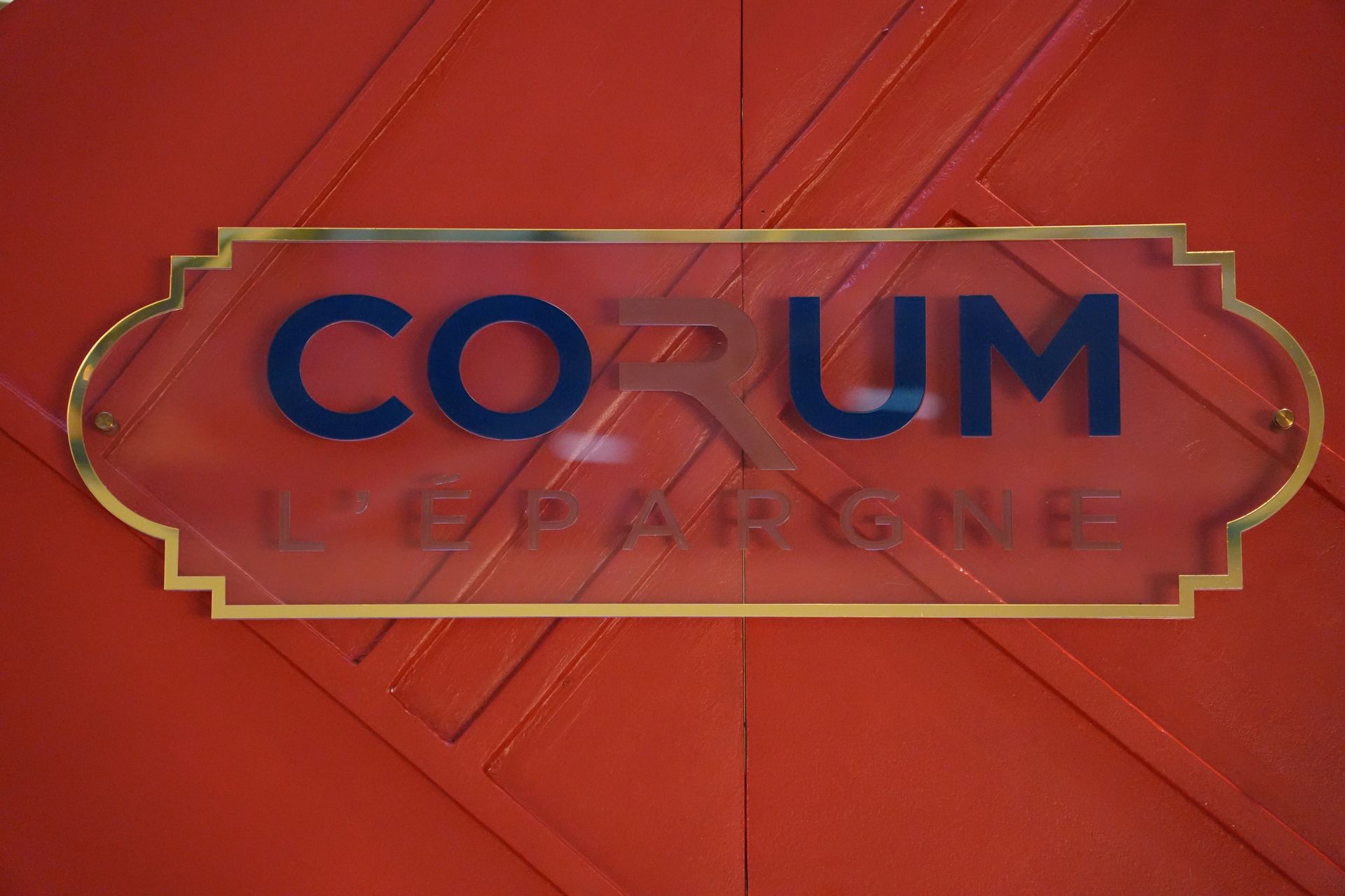 Panneau mural rouge avec inscription « COTUM » en bleu et bordure dorée