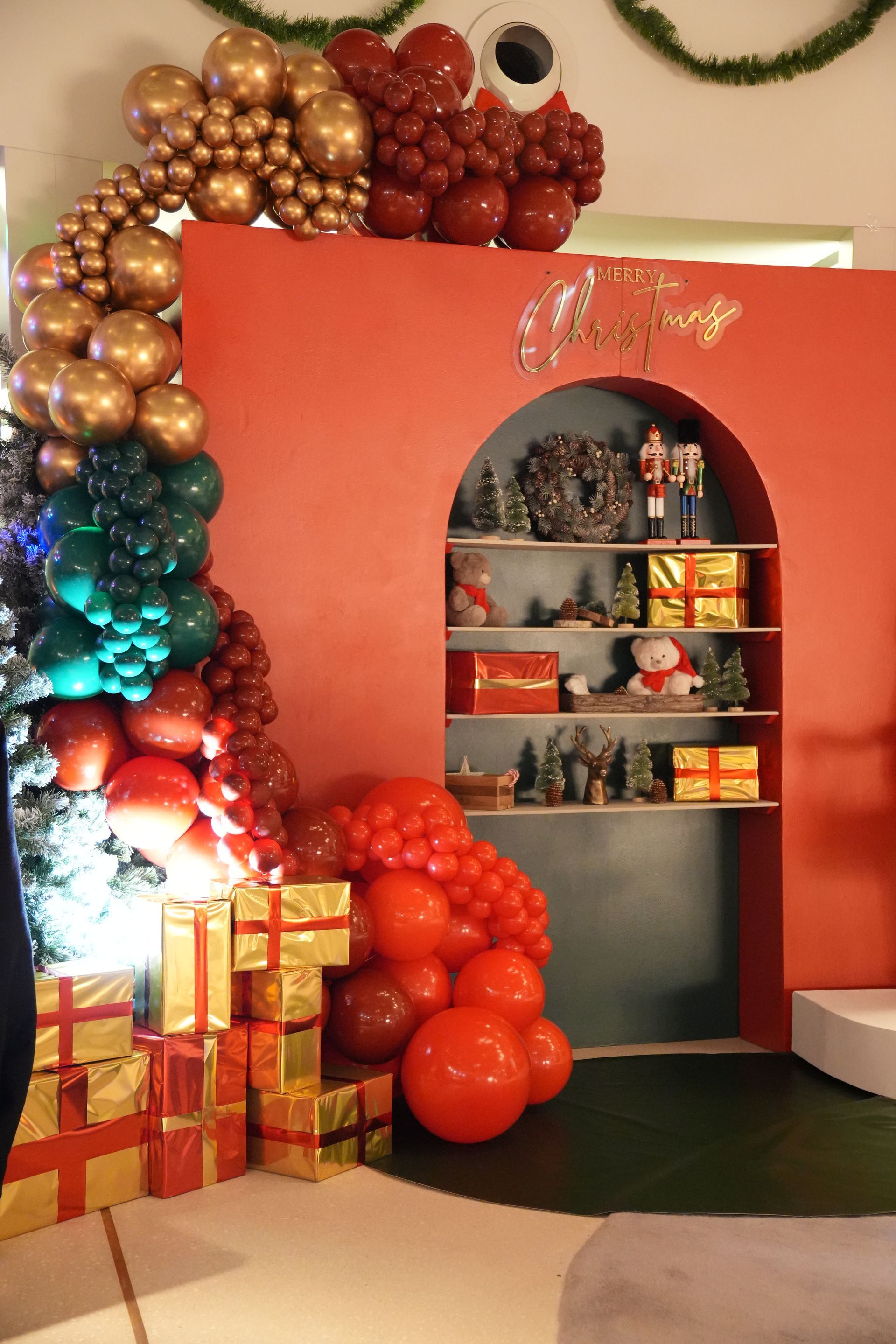 Décoration festive pour les fêtes avec des guirlandes de ballons colorés, des boîtes cadeaux et une étagère murale arquée ornée de décorations.