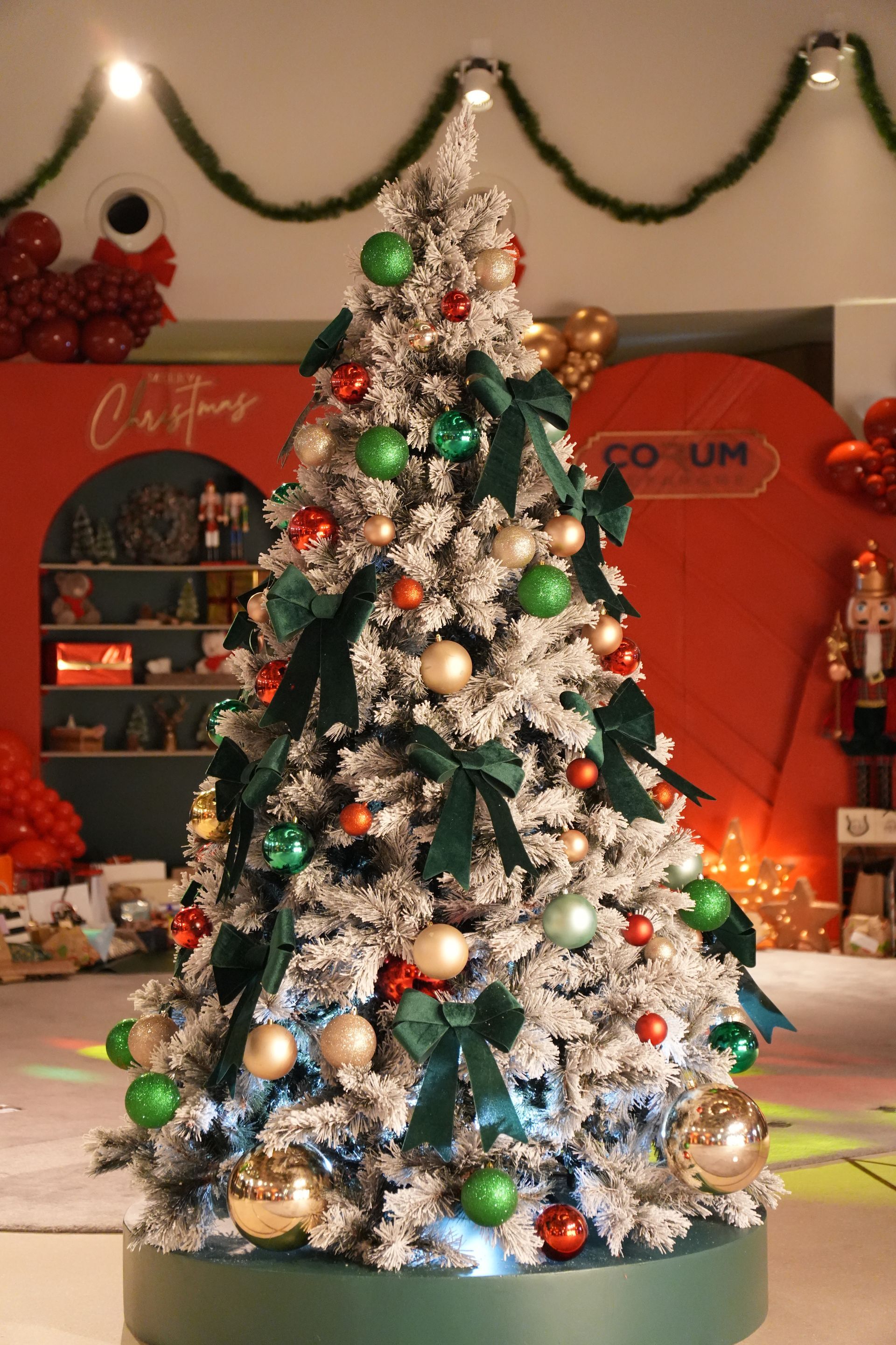 Sapin de Noël décoré de guirlandes argentées, d'ornements et de lumières dans une vitrine intérieure festive