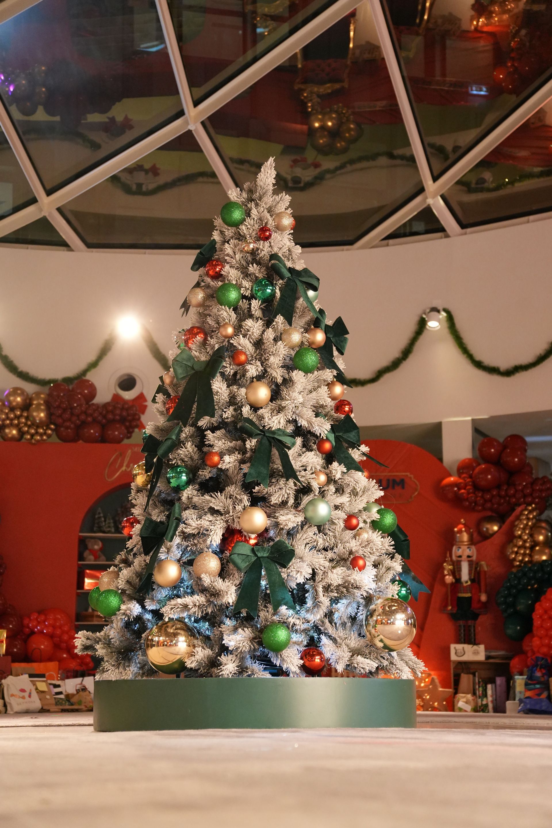 Sapin de Noël décoré de boules et de lumières colorées dans une vitrine intérieure festive