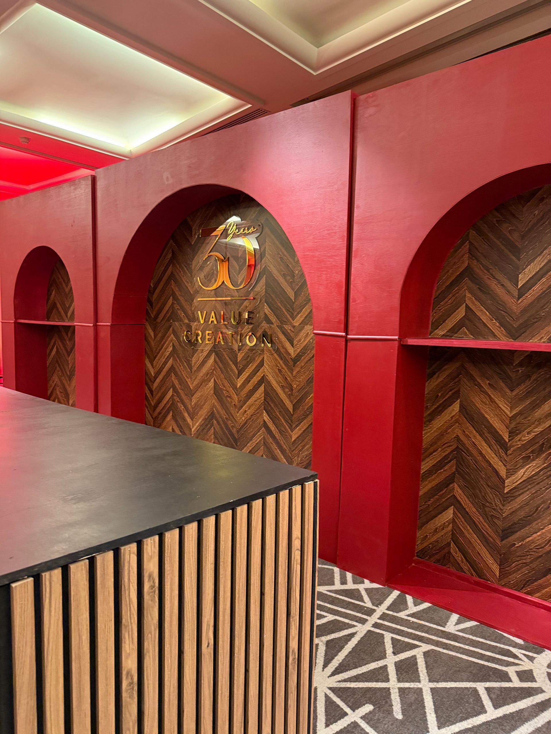 Intérieur aux murs rouges avec niches cintrées, éléments en bois et moquette à motifs à côté d'un comptoir noir