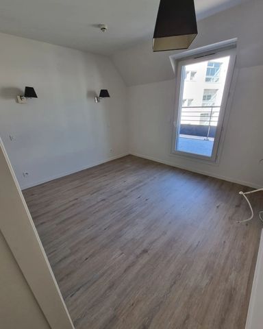 Une pièce vide et bien éclairée, dotée d'un sol clair imitation bois, de deux appliques murales et d'une fenêtre donnant sur un balcon.