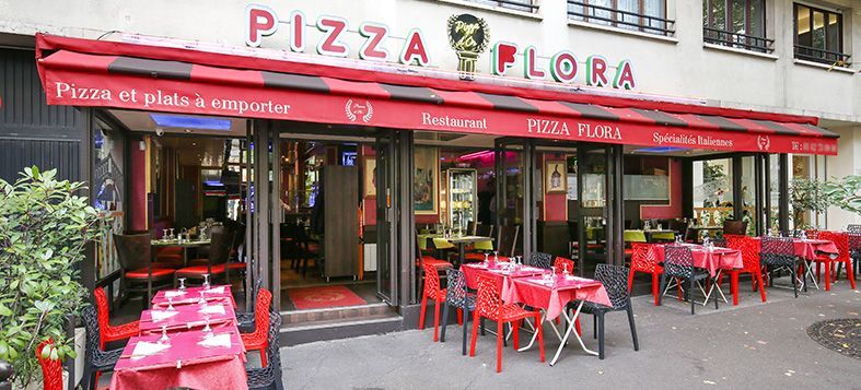 Façade du restaurant Pizza Flora avec un auvent rouge et des tables et chaises de terrasse rouges