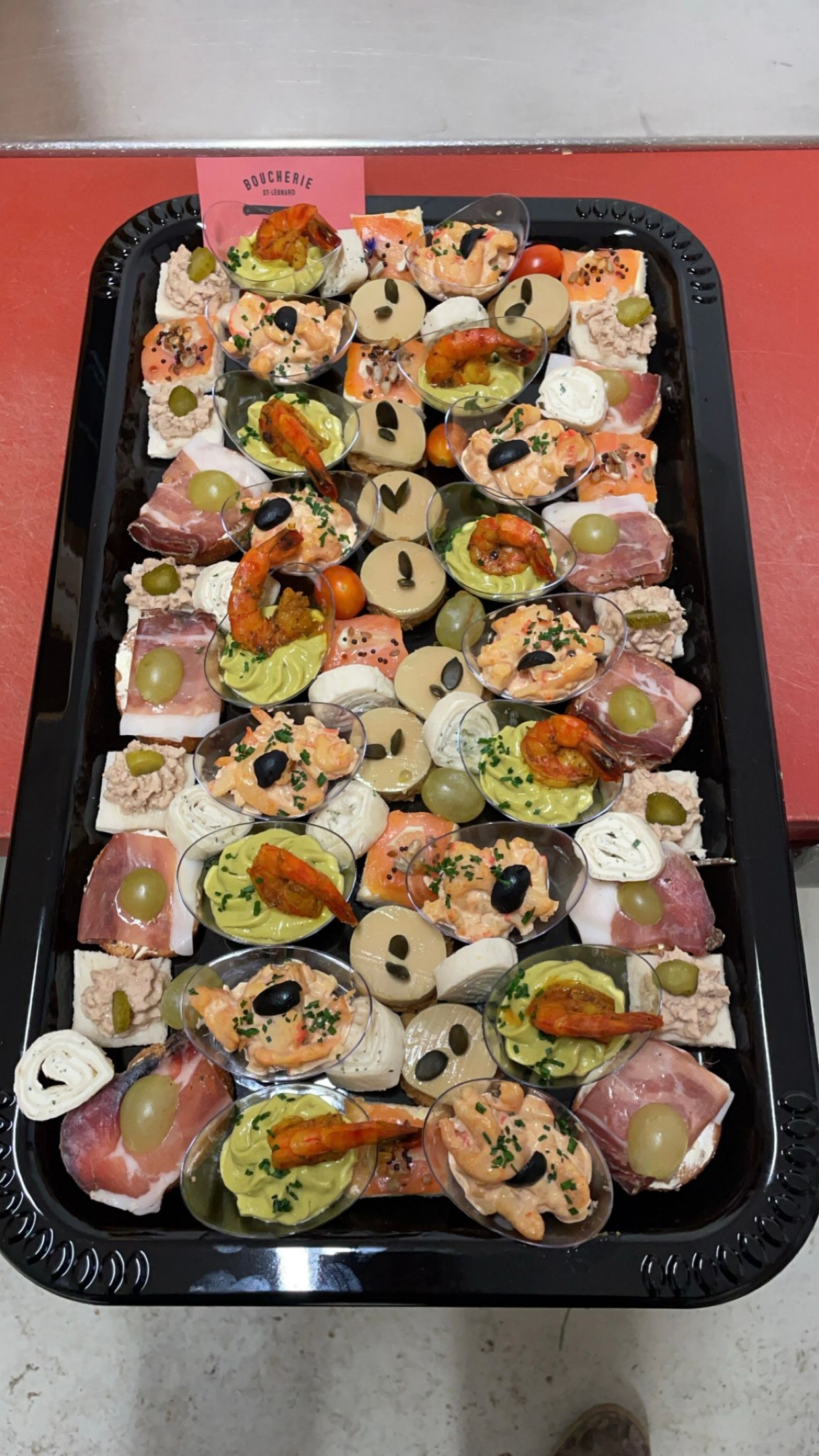 Un plateau noir rempli d'une variété d'aliments sur une table rouge.