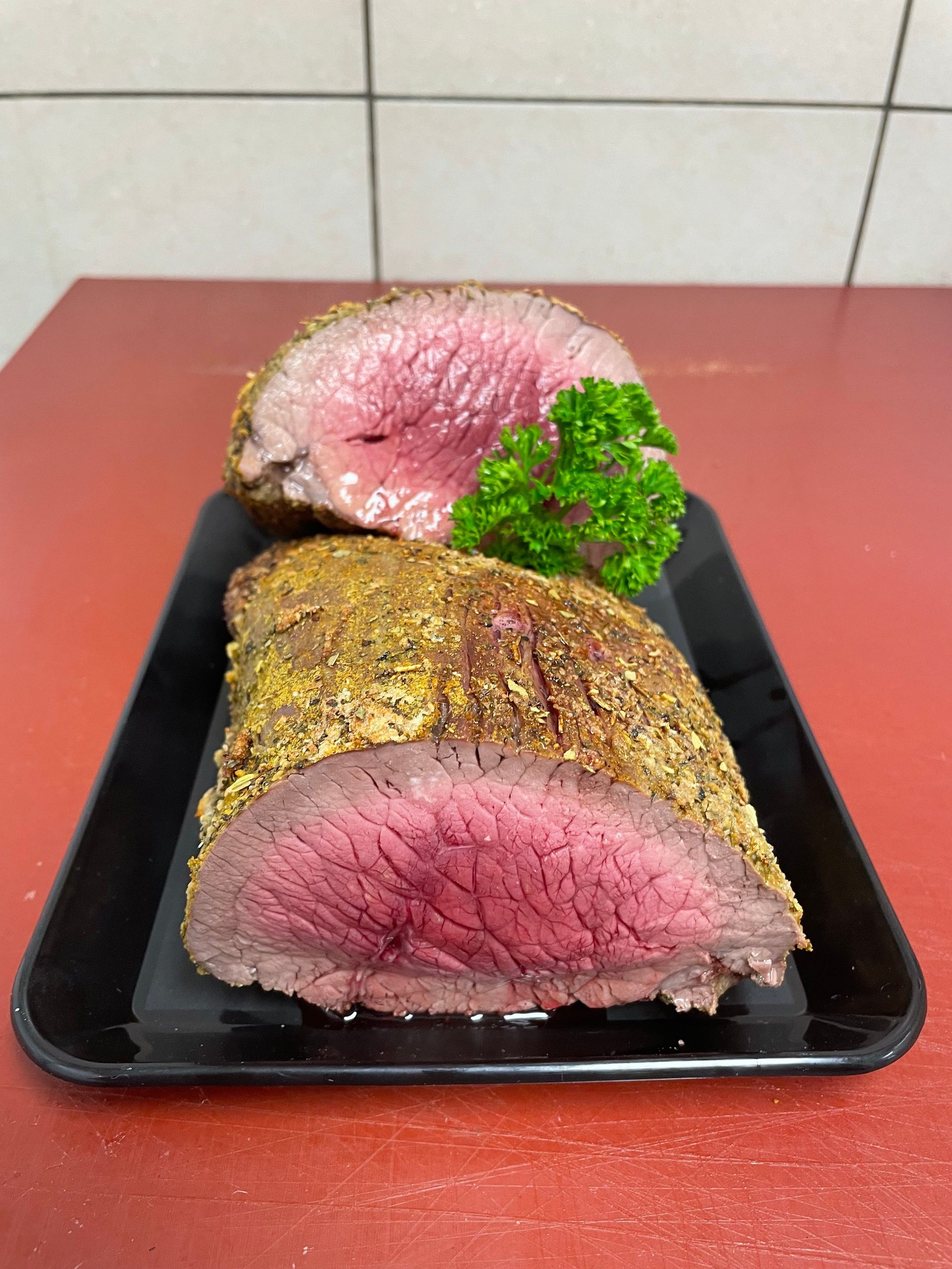 Un morceau de viande est posé sur un plateau noir sur une table.