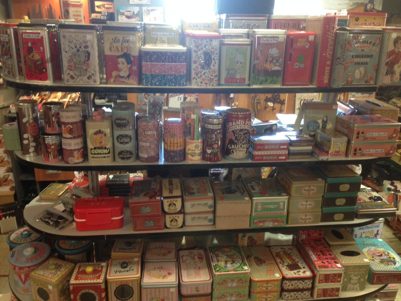 Des étagères remplies de boîtes et de conserves colorées dans une vitrine, les articles cadeaux étant empilés serrés.