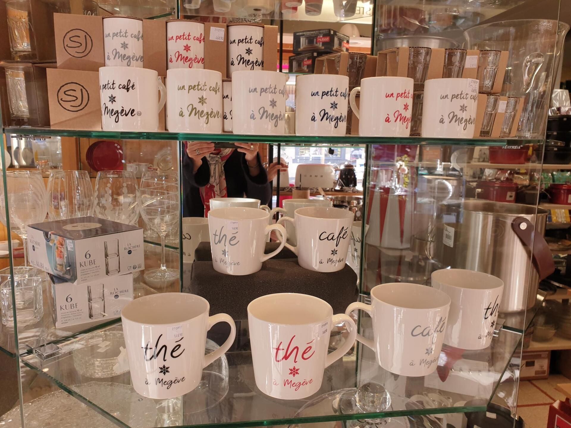 Tasses et verres présentés sur des étagères dans une vitrine.