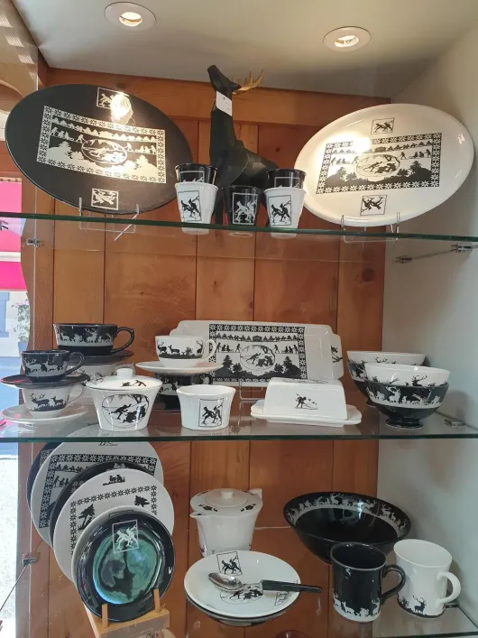 Étagère de présentation de bols, assiettes, tasses et plaques décoratives en céramique noire et blanche dans un magasin.