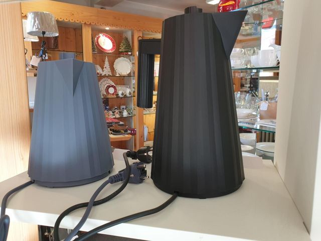 Deux carafes, l'une bleu et l'autre noir, posés sur une table dans un magasin ou une salle d'exposition.