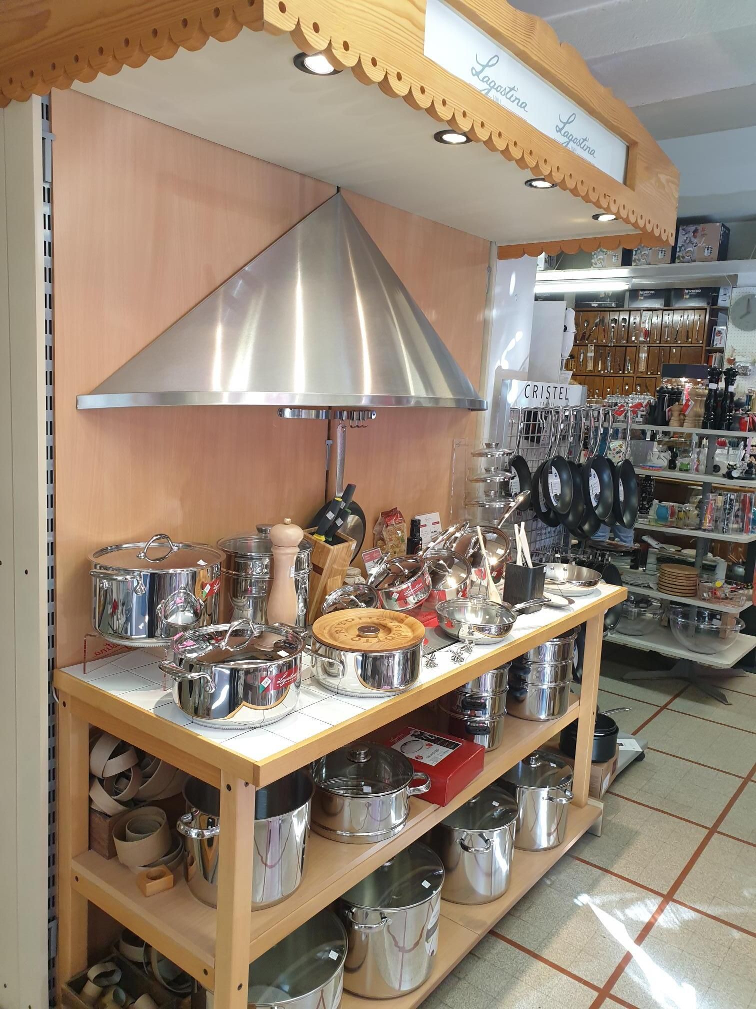 Cuisine aménagée avec hotte en acier inoxydable au-dessus d'un comptoir en bois présentant ustensiles de cuisine.