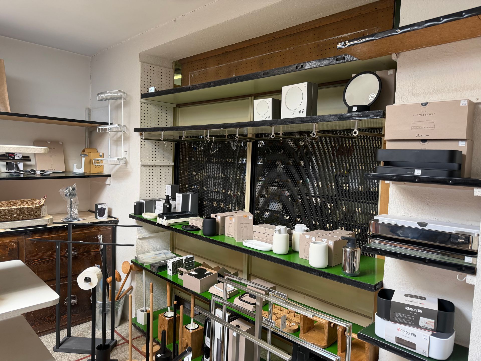 Magasin avec étagères, cafetière, vaisselle et bocaux sur un comptoir et rangements muraux.