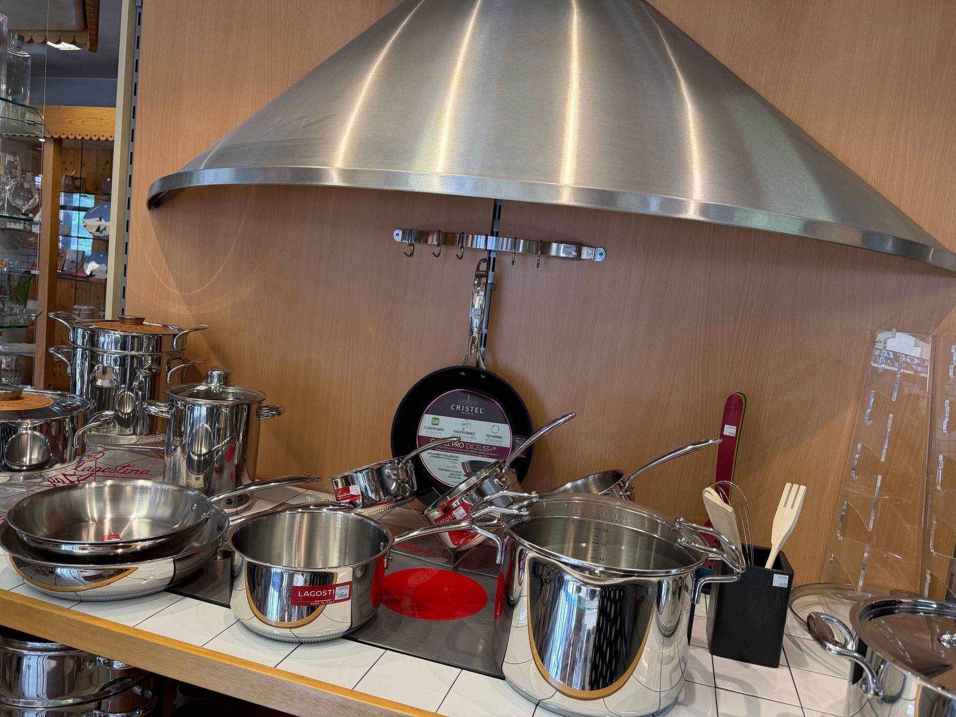 Plan de travail avec ustensiles et bols en inox sous une grande hotte argentée.