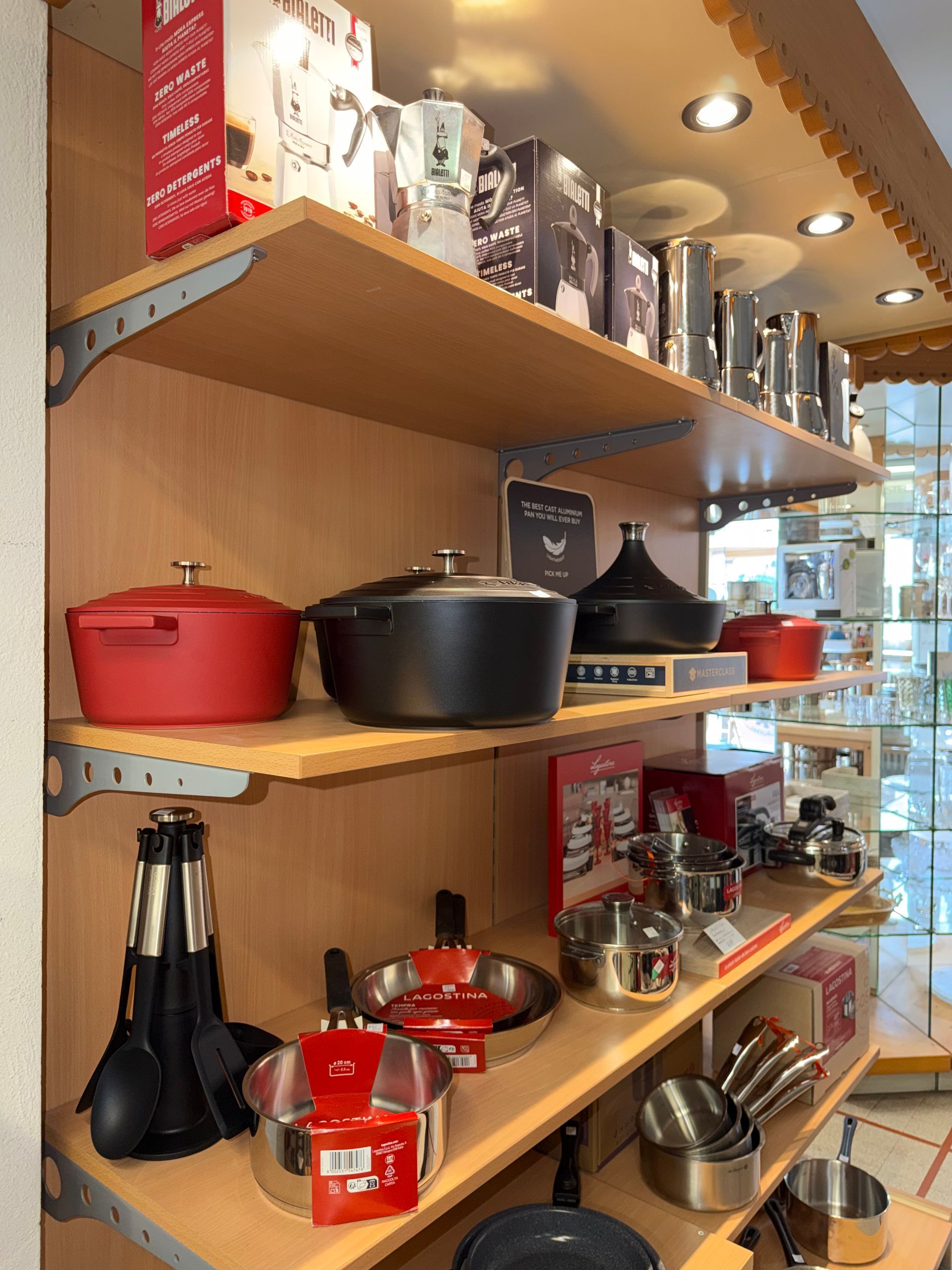 Rayons d'articles de cuisine et de casseroles dans un magasin, comprenant notamment des casseroles, des poêles et des ustensiles.