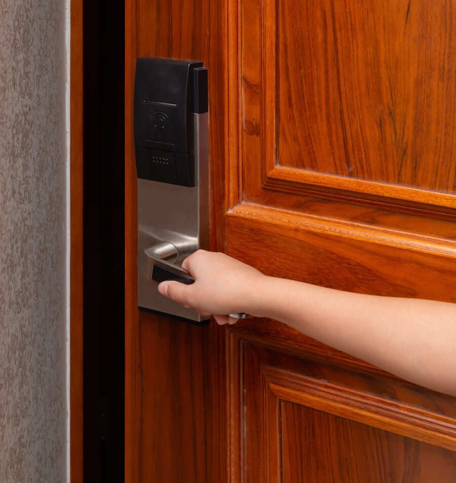 Une main ouvre une porte en bois équipée d’une serrure électronique argentée