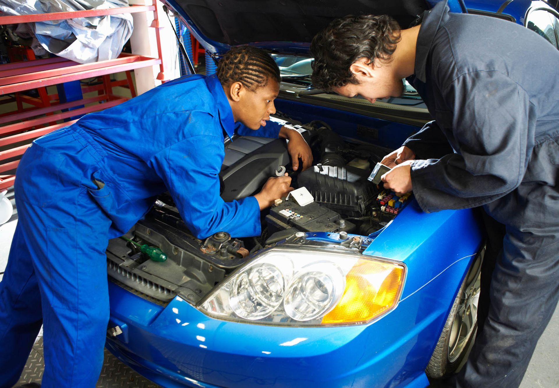 Zwei Mechaniker arbeiten in einer Garage an einem blauen Auto