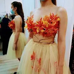 Mujer con un top floral y una falda amarilla, de pie junto a otra mujer con un vestido amarillo.