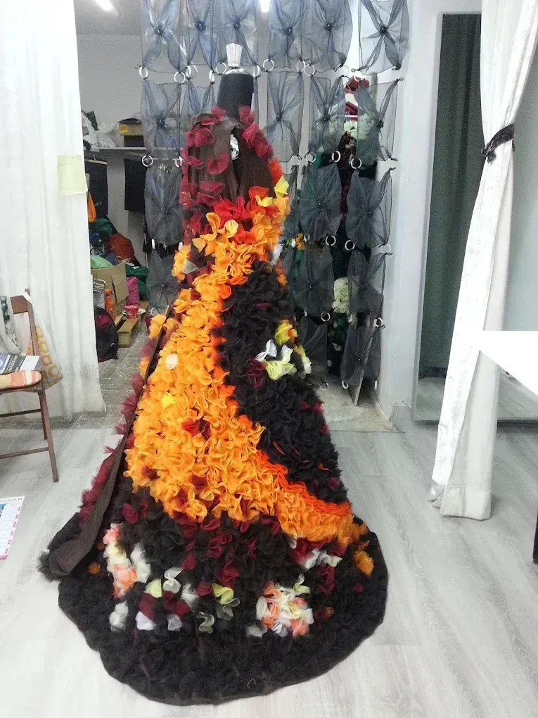 Maniquí con vestido largo con detalles negros, naranjas y florales, expuesto en una tienda.