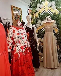 Exhibición de tienda de ropa con maniquíes luciendo vestidos, incluido uno rojo con flores.