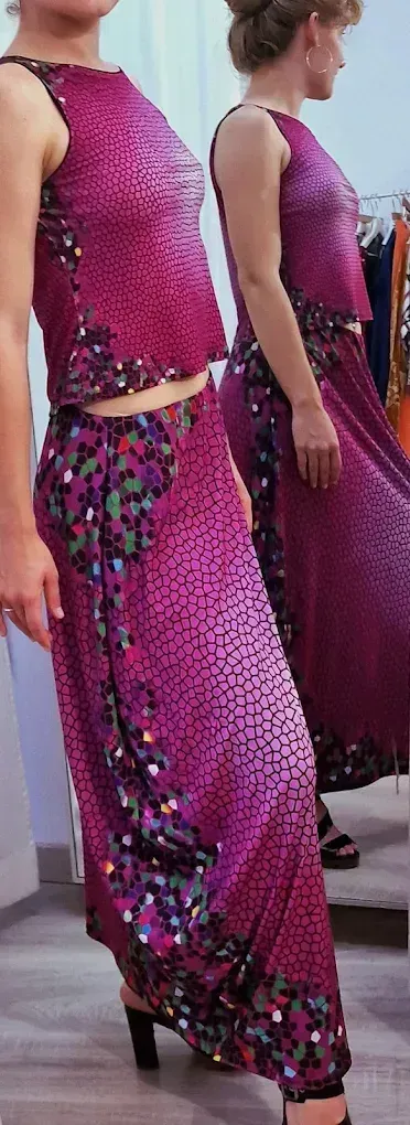 Mujer con un conjunto de dos piezas color magenta con un adorno floral. De pie frente a un espejo.