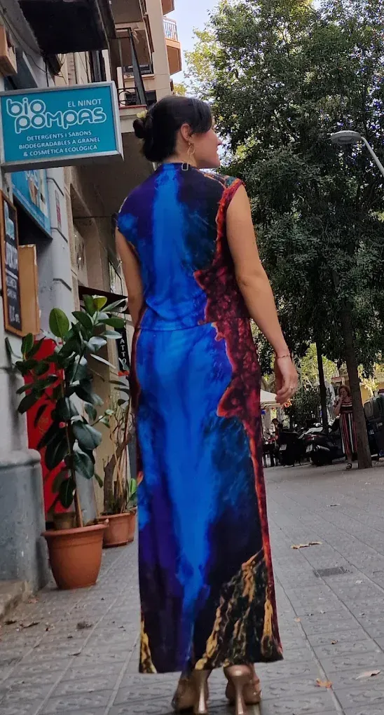Una mujer con un vestido azul y rojo está parada en una acera.