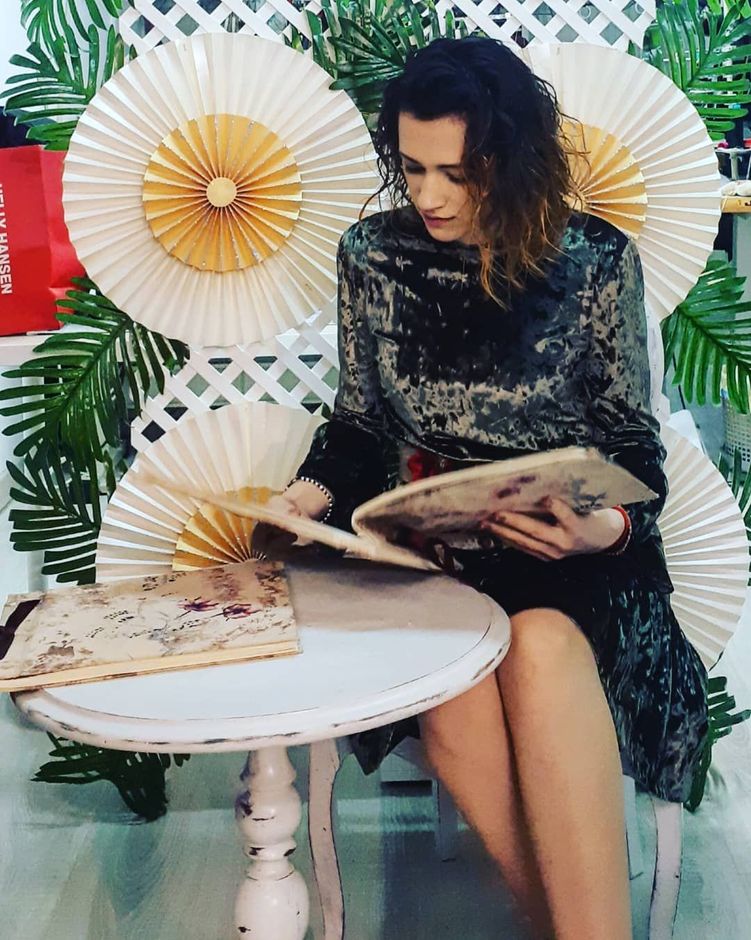 Una mujer está sentada en una mesa leyendo un libro.