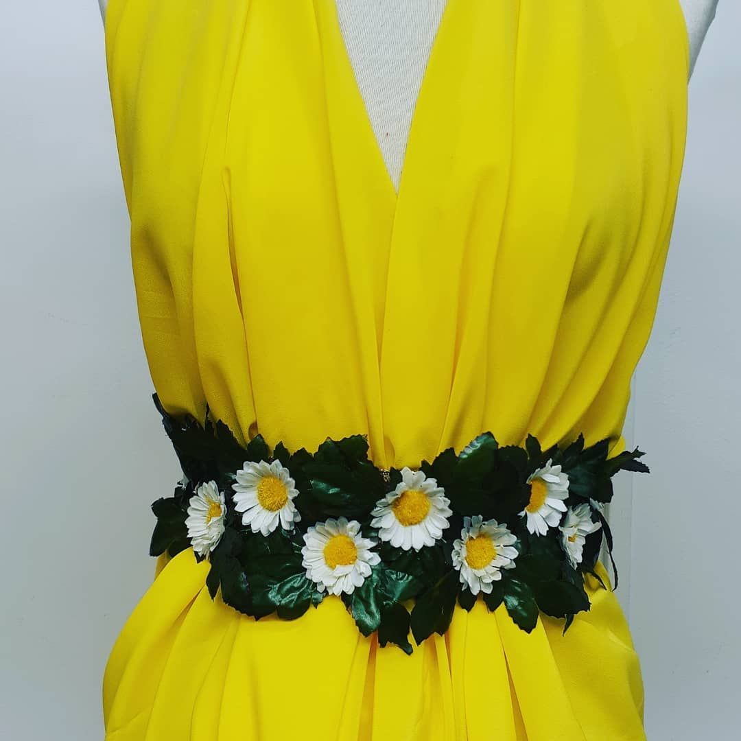 Un vestido amarillo con un cinturón floral alrededor de la cintura.