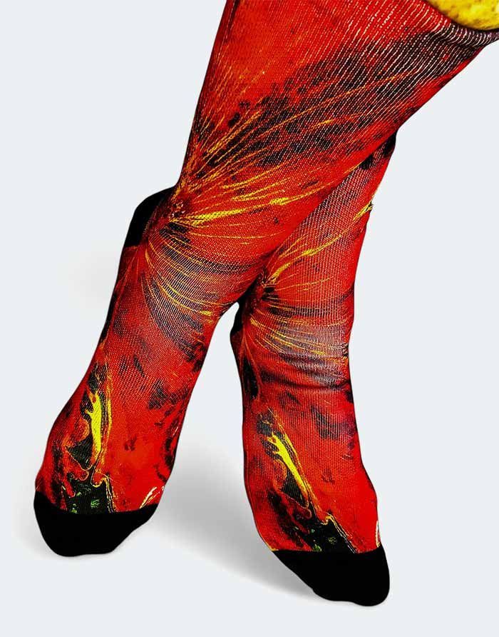 Pies en medias de color rojo brillante con un diseño abstracto amarillo y negro, cruzados en los tobillos.