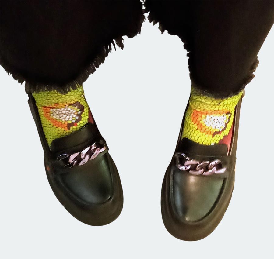 Mocasines negros con detalle de cadena plateada, combinados con calcetines estampados en amarillo y naranja.