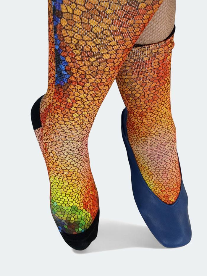 Pies con calcetines con estampado de escamas de peces y bailarinas azules; un pie apuntando hacia arriba.